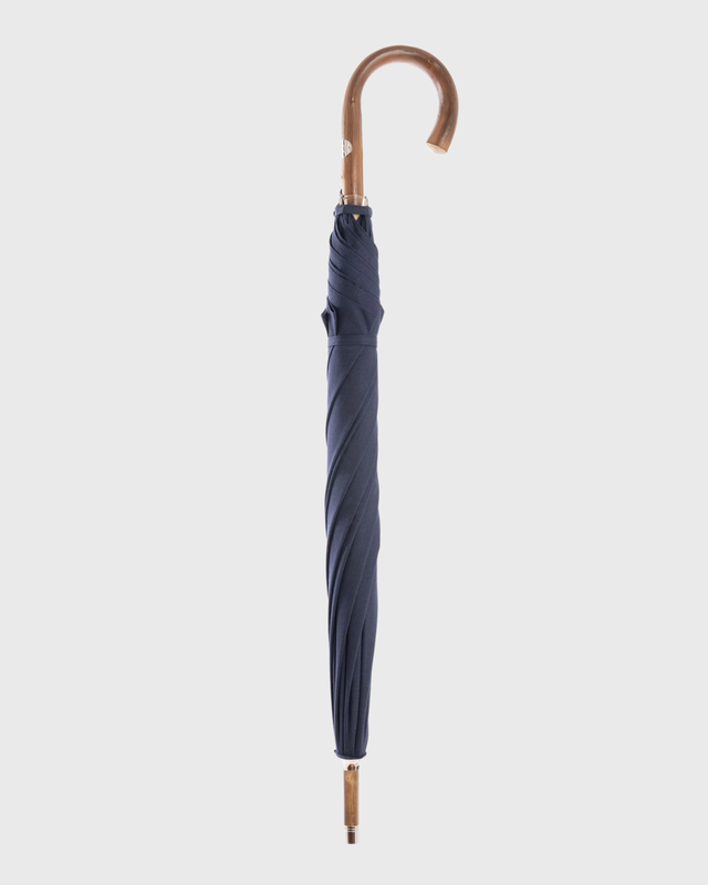 A closed navy blue umbrella with a curved brown wooden handle, shown vertically against a light gray background.