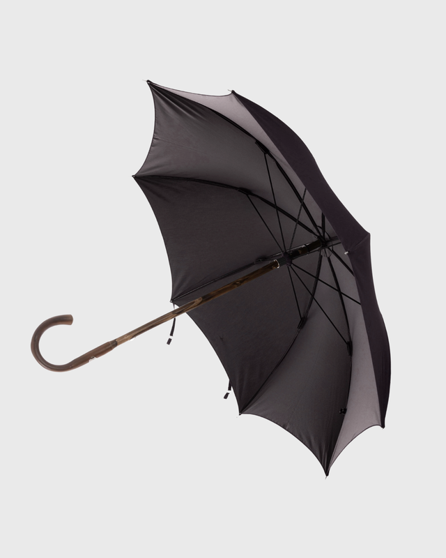 A classic open umbrella with a dark charcoal gray canopy, a brown wooden handle, and black ribs, shown against a solid light gray background.